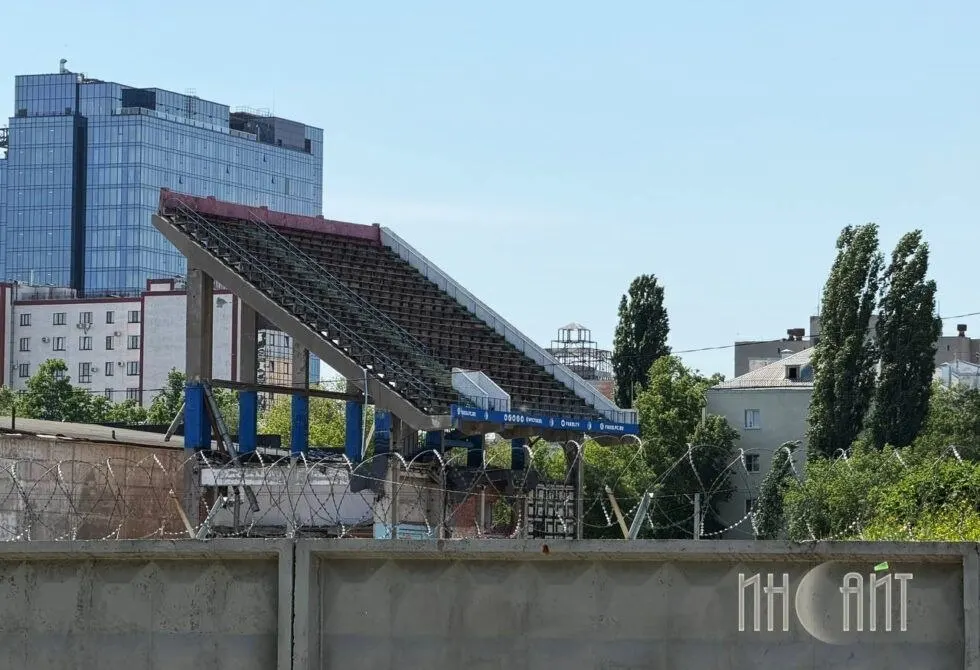 Демонтаж Восточной трибуны приостановлен: две частные кирпичные постройки оказались конструктивно связаны со зданием, подрядчик не может задействовать тяжёлую технику, а вопрос выкупа земли зашёл в юридический тупик.